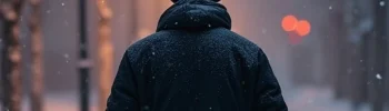 Man seen from behind, walking on a snowy path under streetlights - AI-generated illustration.