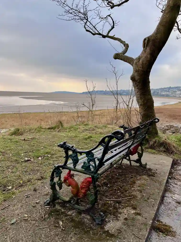 Grange-over-Sands seen from a distance with a Victorian bench in the foreground.