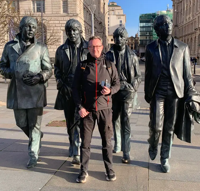 Tom in front of the statues of the Beatles members in Liverpool