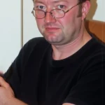 AI-generated illustration showing Tom as he looked in 2005, sitting in an armchair, looking sad