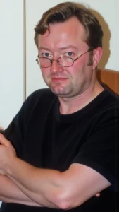 AI-generated illustration showing Tom as he looked in 2005, sitting in an armchair, looking sad